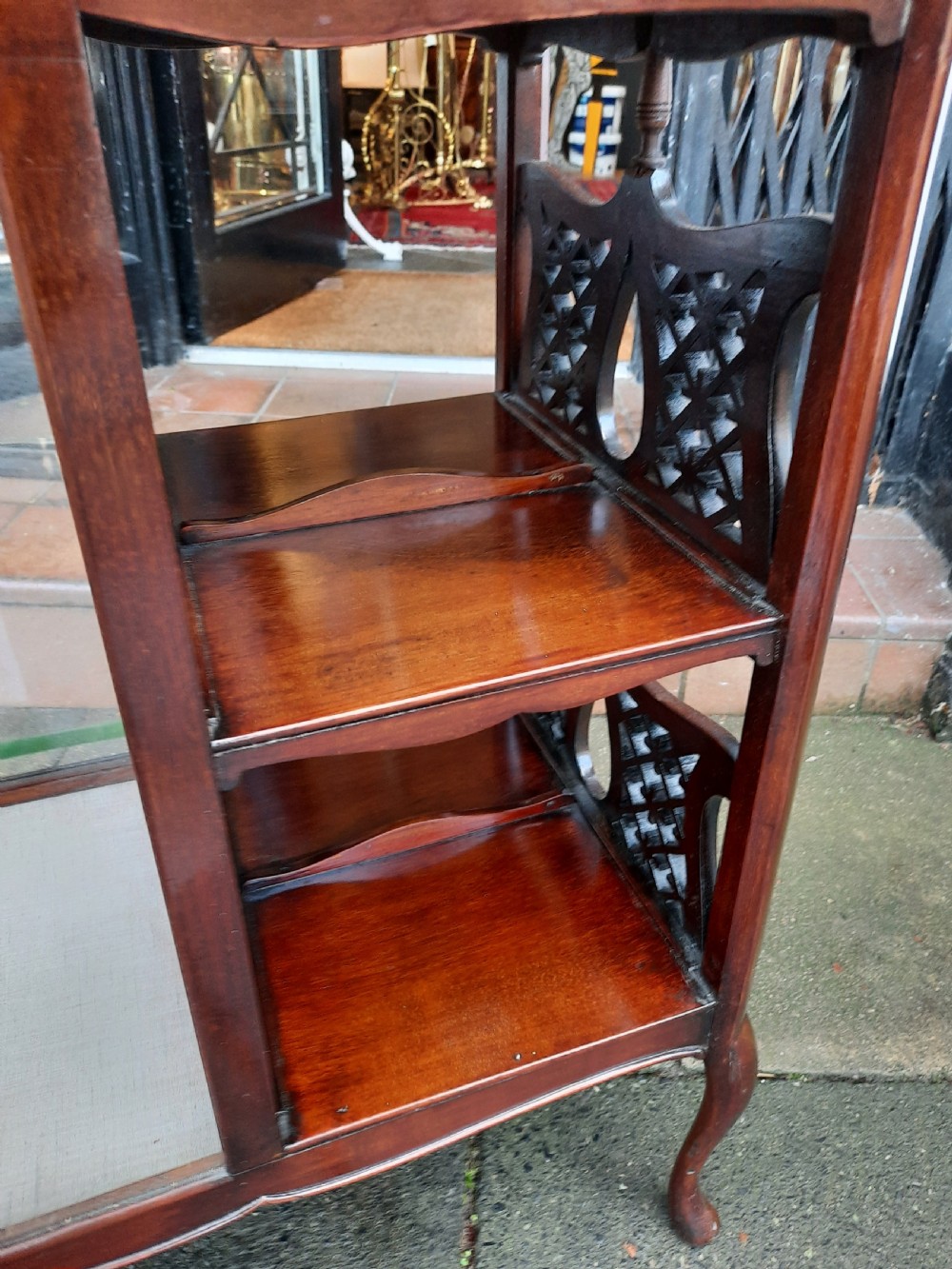 An Edwardian mahogany display table featuring a single-door glazed cabinet on the left and open two-tier shelving with pierced fretwork on the right, supported by cabriole legs. View III