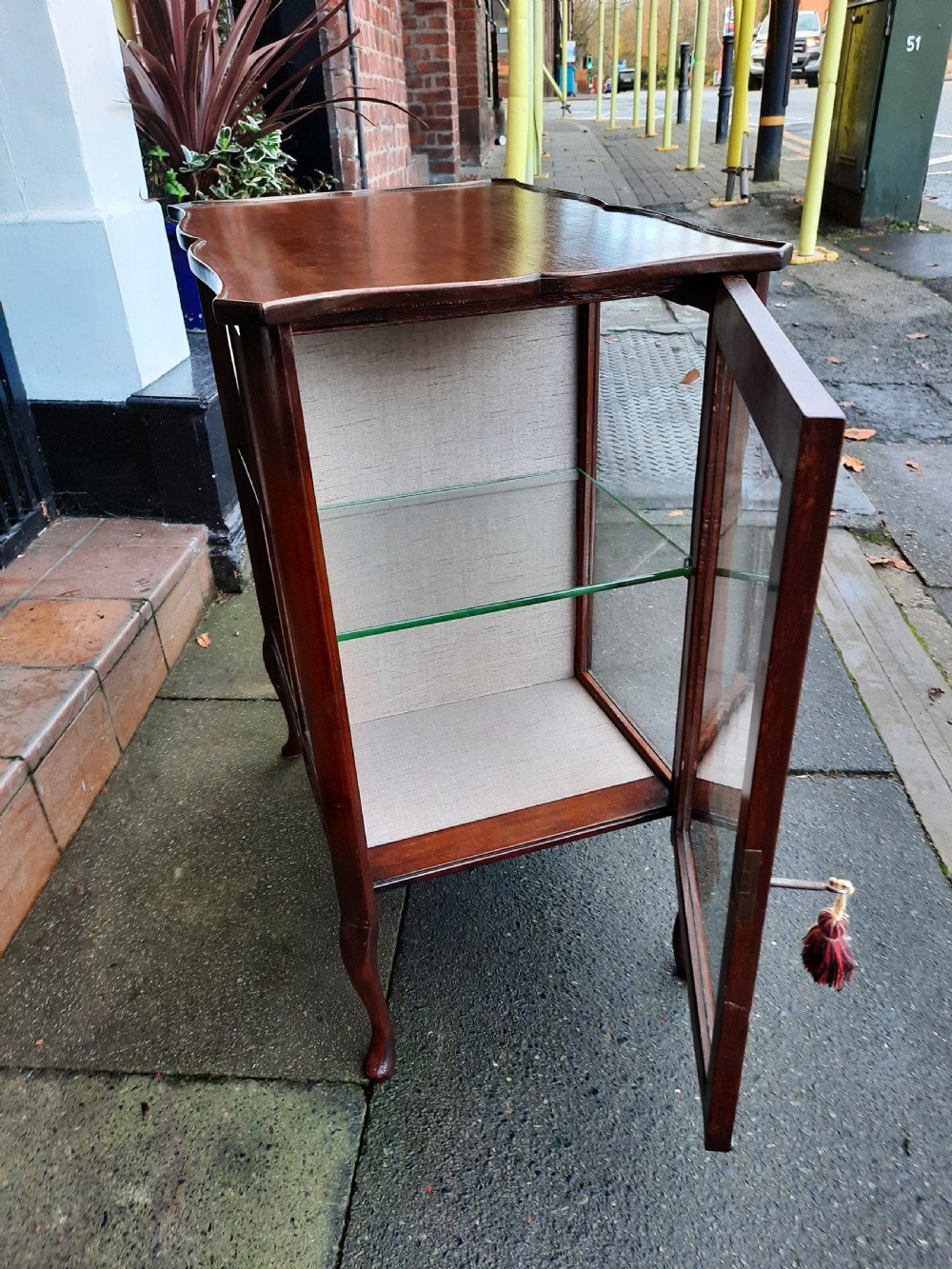 An Edwardian mahogany display table featuring a single-door glazed cabinet on the left and open two-tier shelving with pierced fretwork on the right, supported by cabriole legs. View V