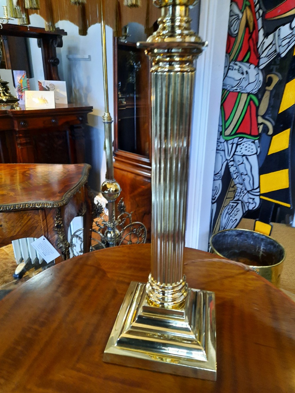 A nineteenth-century brass table lamp featuring a fluted column support, square stepped base, and a decorated fabric shade with hanging fringe. View III