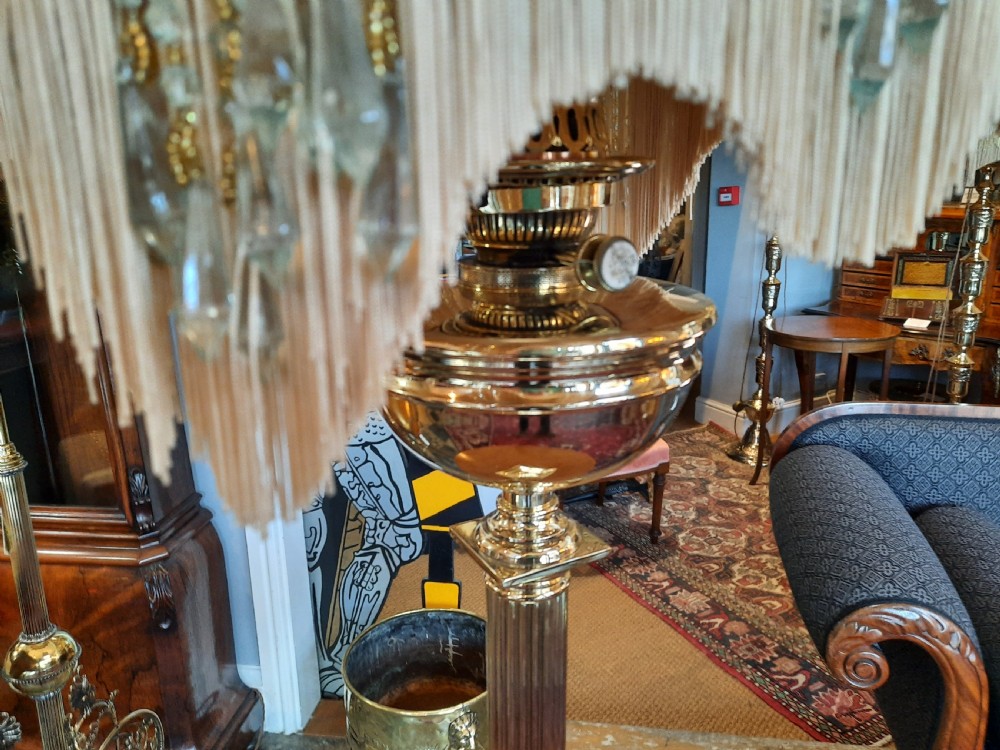 A nineteenth-century brass table lamp featuring a fluted column support, square stepped base, and a decorated fabric shade with hanging fringe. View IV