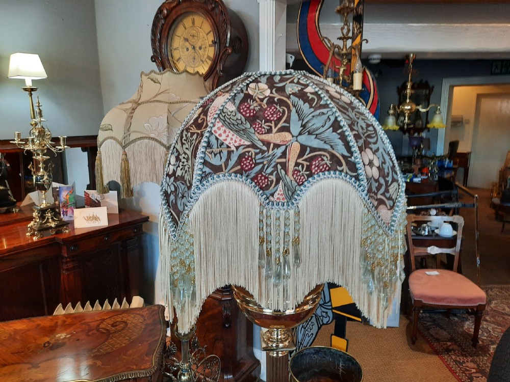 A nineteenth-century brass table lamp featuring a fluted column support, square stepped base, and a decorated fabric shade with hanging fringe. View V