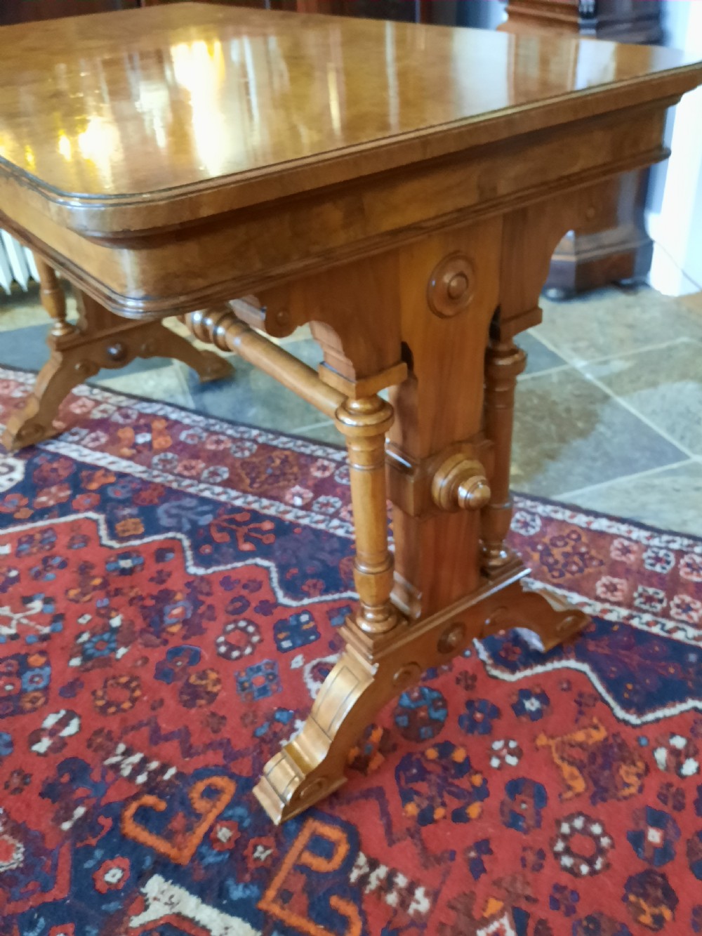 A Victorian walnut centre sofa table featuring a rectangular figured veneer top, turned stretcher, carved end supports, and dual feet. View II