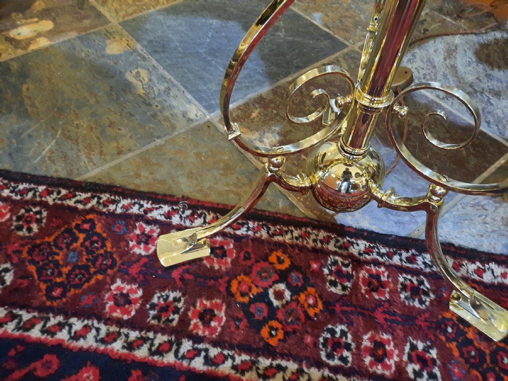 An Edwardian brass extending standard lamp featuring a scrolled tripod base and a burgundy dome fabric shade with fringe tassels. View II