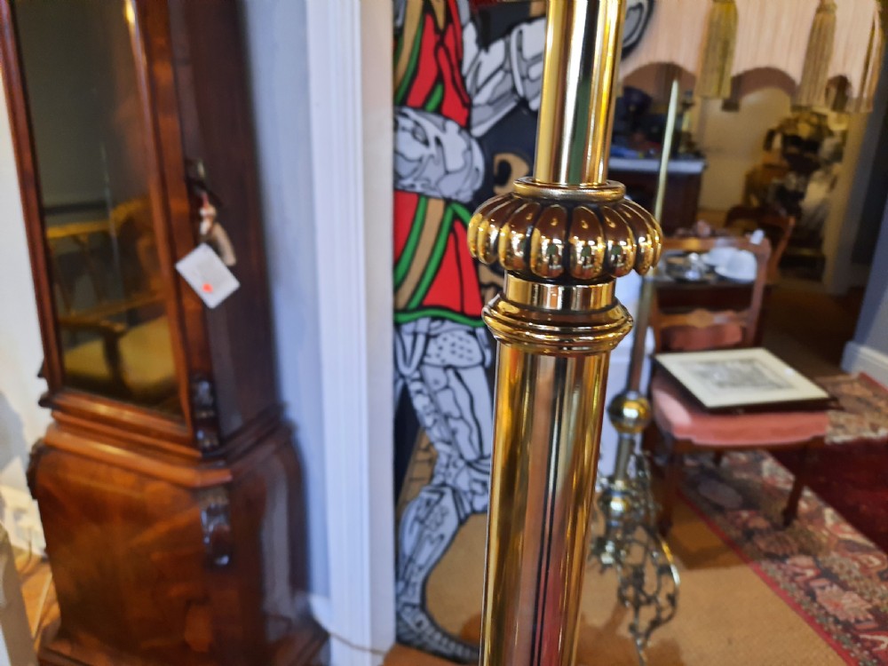 An Edwardian brass extending standard lamp featuring a scrolled tripod base and a burgundy dome fabric shade with fringe tassels. View IV