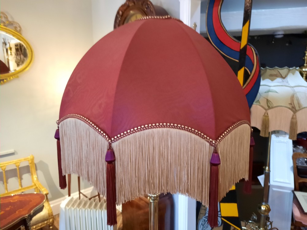 An Edwardian brass extending standard lamp featuring a scrolled tripod base and a burgundy dome fabric shade with fringe tassels. View V
