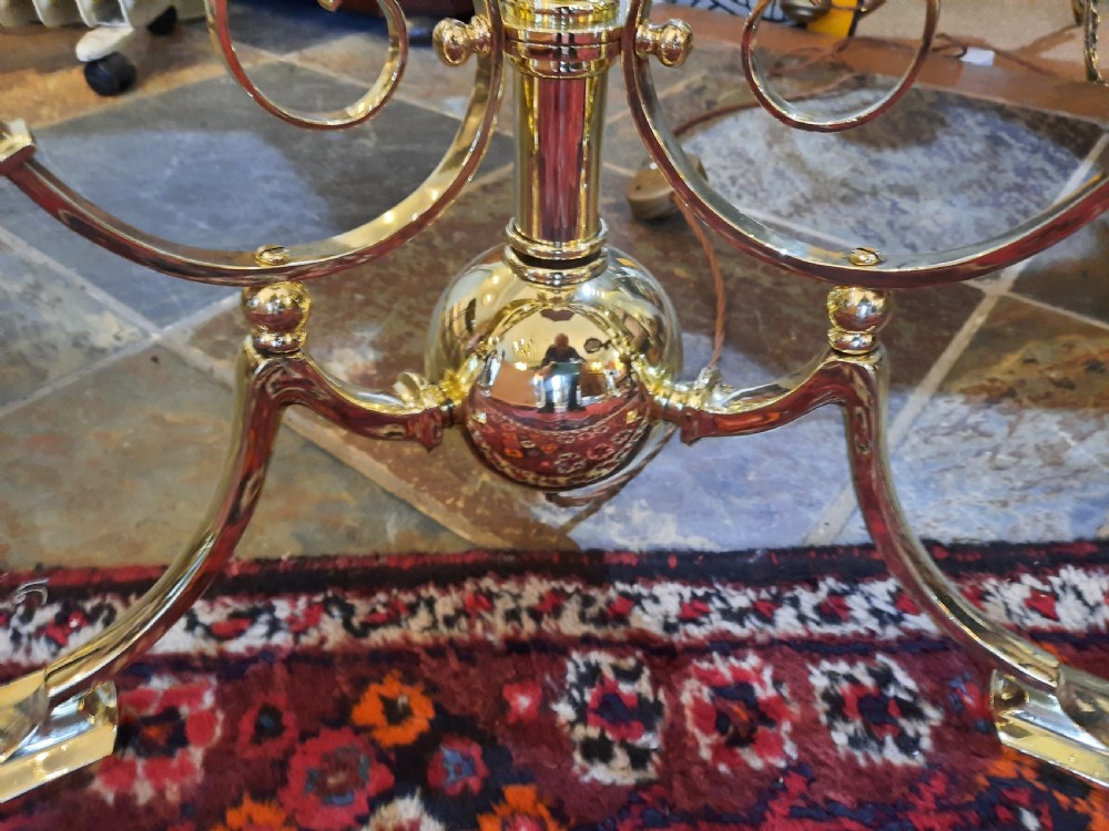 An Edwardian brass extending standard lamp featuring a scrolled tripod base and a burgundy dome fabric shade with fringe tassels. View VI