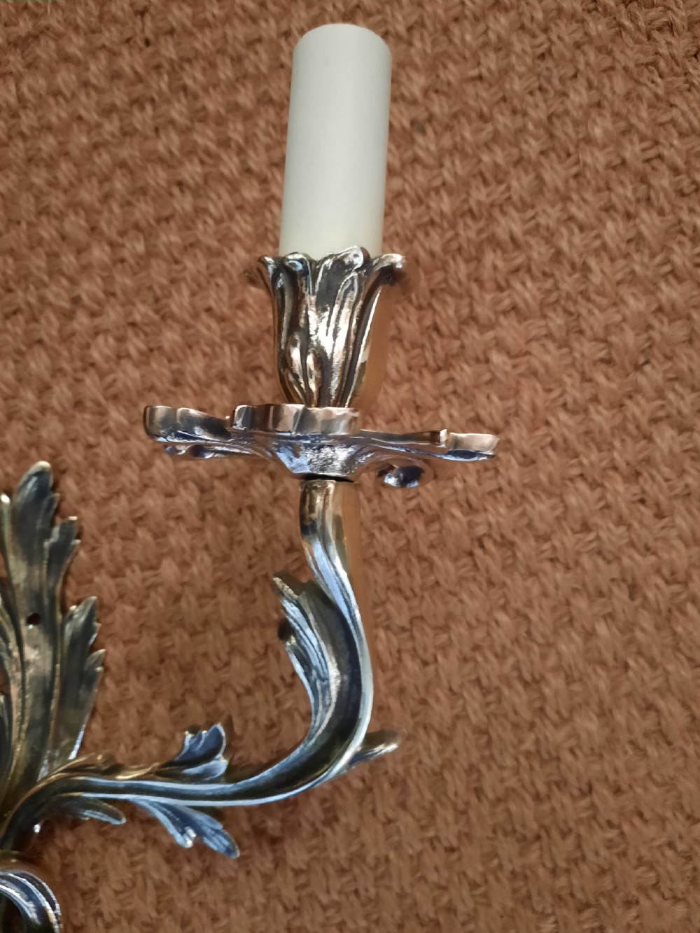 A cast brass twin-arm wall light in the Rococo Revival style featuring scrolling acanthus foliage and white faux candle sockets. View II