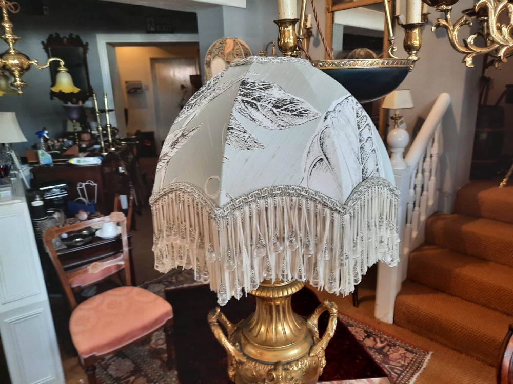 A 19th-century gilt bronze classical urn mounted as a table lamp on a square marble base with a fringed fabric shade. View II