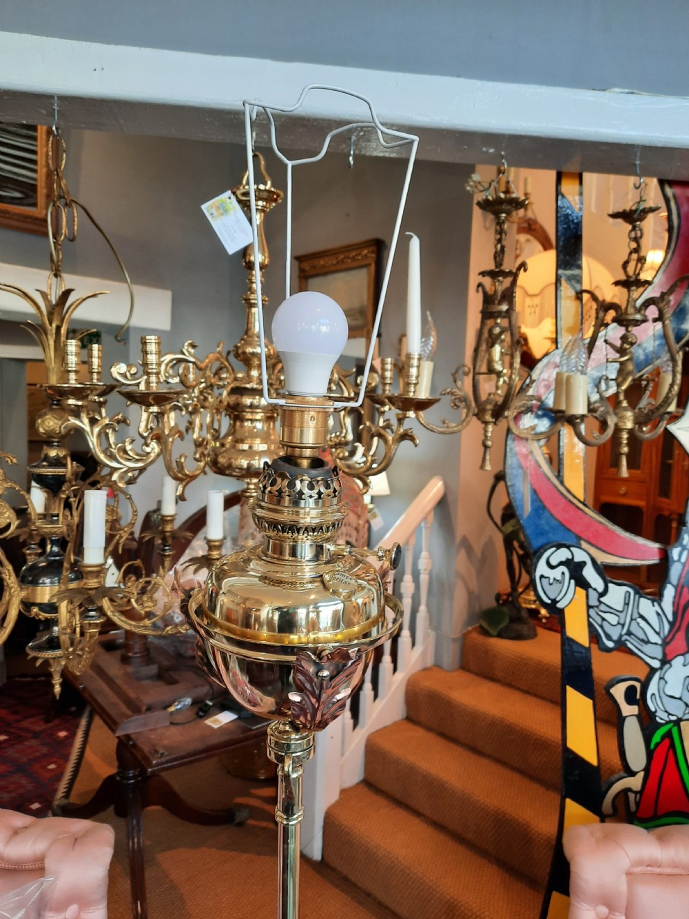 An antique Arts and Crafts adjustable brass floor lamp featuring a tripod base, twisted support column, and a dome-shaped red fabric shade with tassel fringe. View III