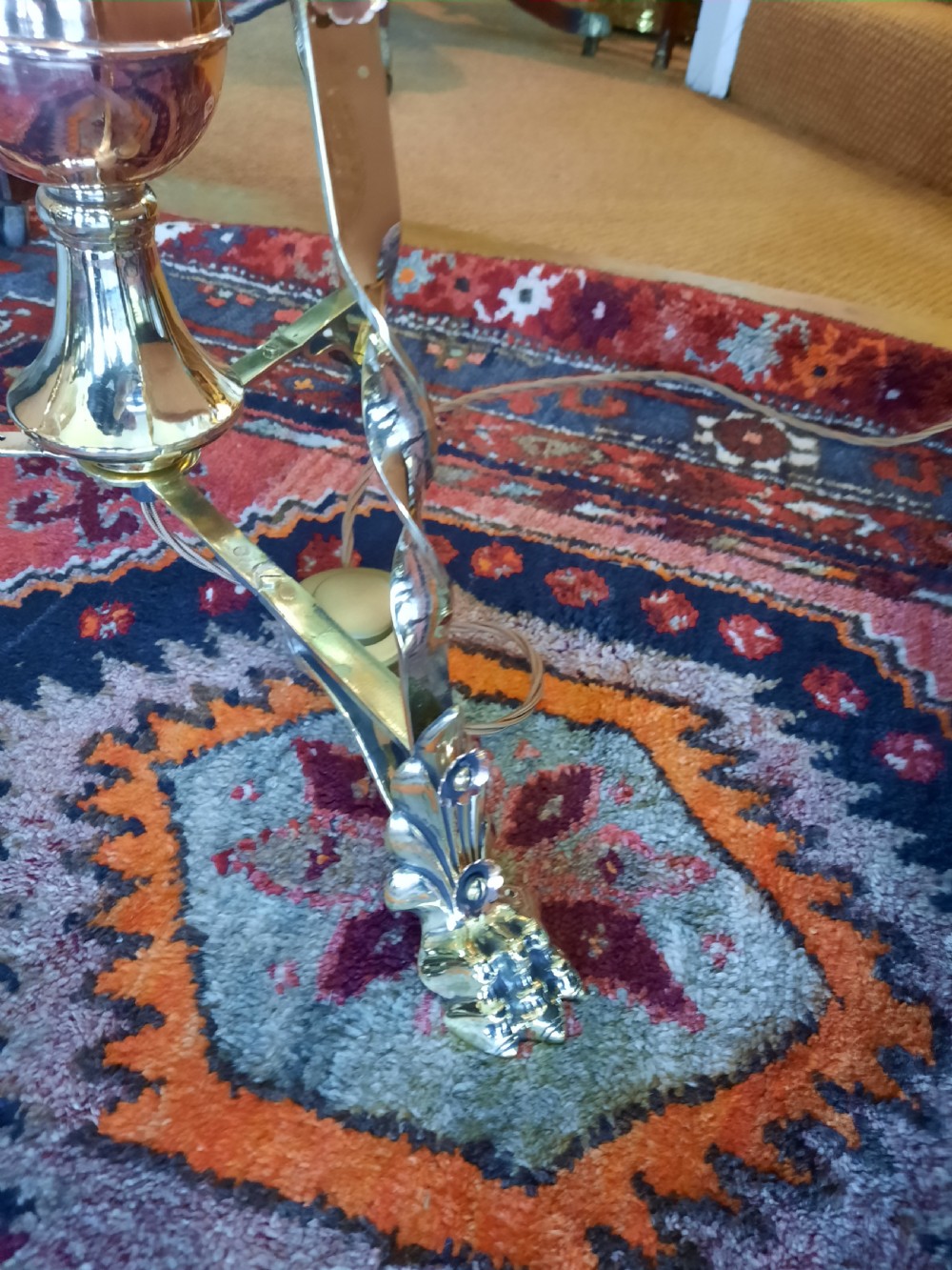 An antique Arts and Crafts adjustable brass floor lamp featuring a tripod base, twisted support column, and a dome-shaped red fabric shade with tassel fringe. View VI