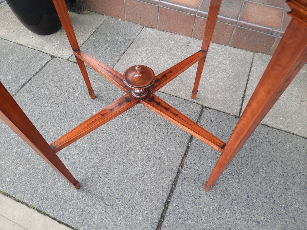 An Edwardian oval satinwood occasional table featuring hand-painted floral decoration on the top, slender tapered legs, and an X-form stretcher with a central wooden urn finial. View VIII
