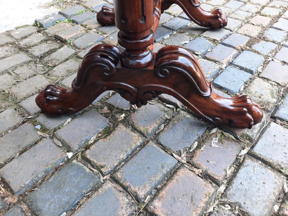 A 19th-century rosewood card table with a fold-over rectangular top, carved scroll apron, turned supports, and carved claw feet. View V