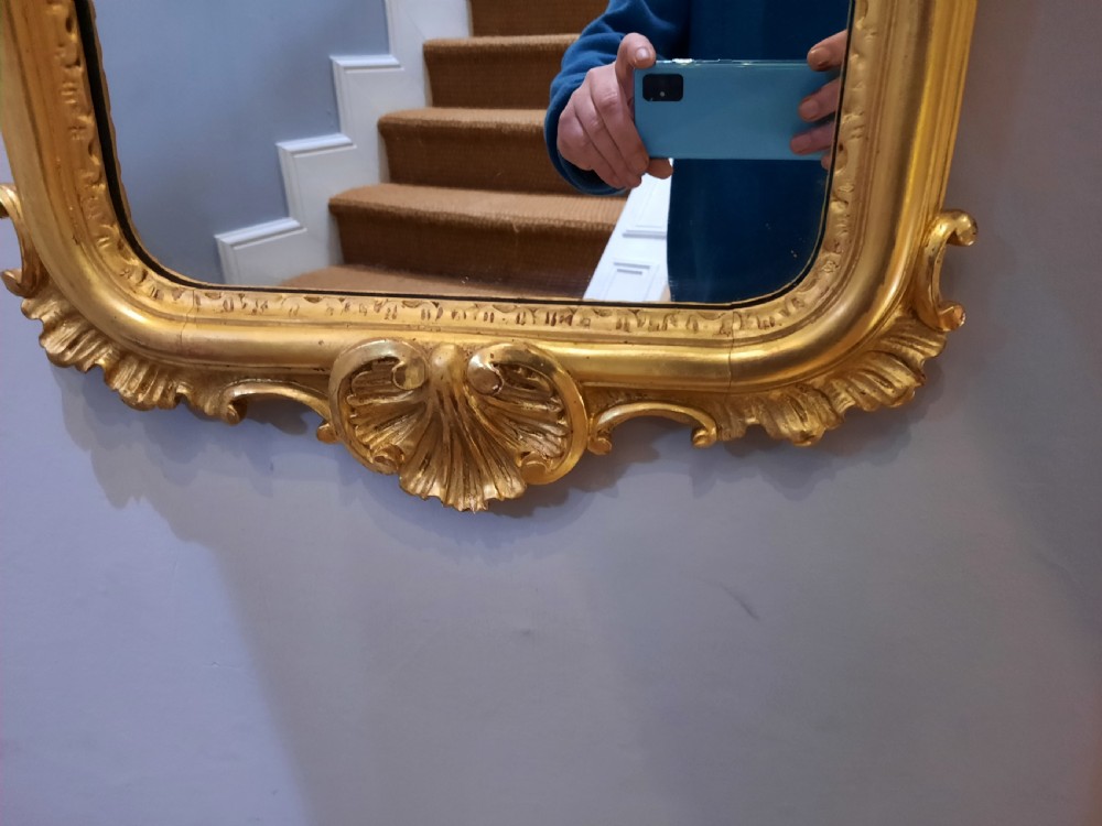 A tall arched late Victorian pier mirror featuring an ornate gold giltwood frame with carved foliate scrolls and a top cresting finial. View II