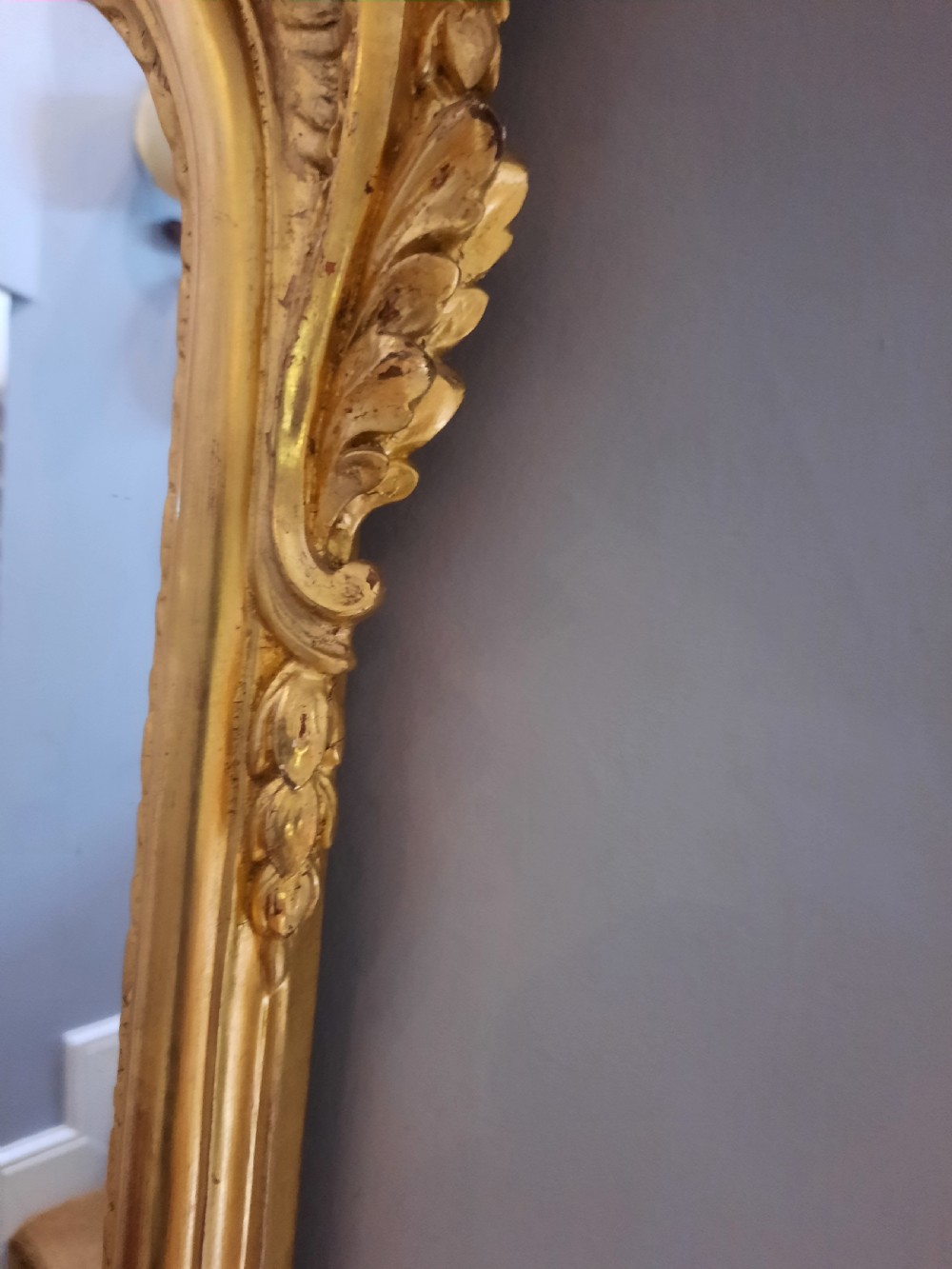 A tall arched late Victorian pier mirror featuring an ornate gold giltwood frame with carved foliate scrolls and a top cresting finial. View III