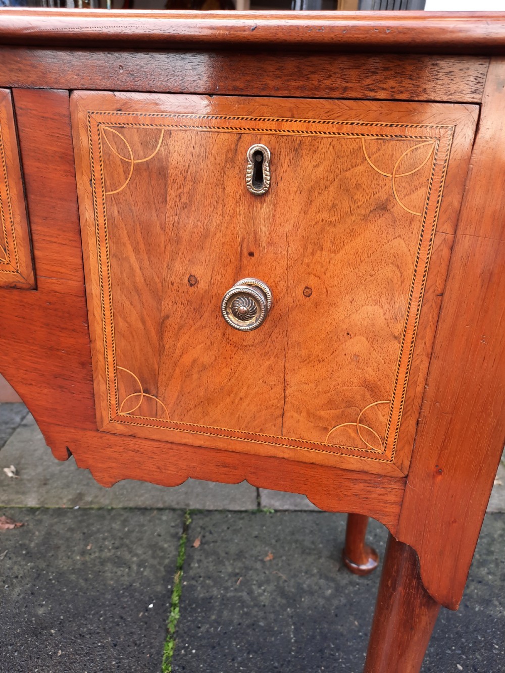 An Edwardian inlaid mahogany lowboy featuring three drawer fronts decorated with lighter wood inlay, an arched apron, and cabriole legs. View IV