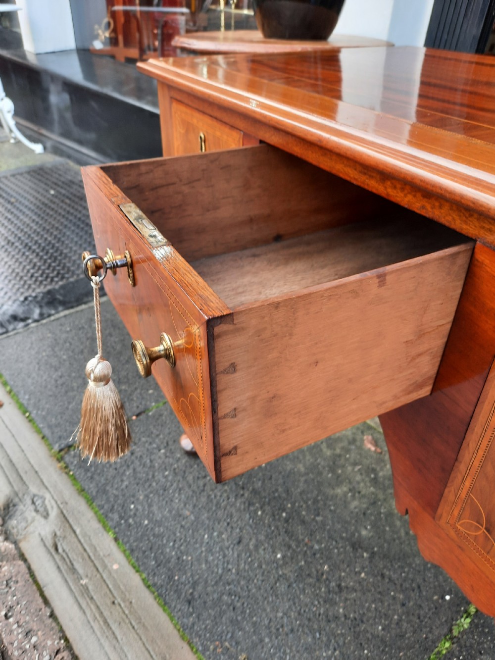 An Edwardian inlaid mahogany lowboy featuring three drawer fronts decorated with lighter wood inlay, an arched apron, and cabriole legs. View V