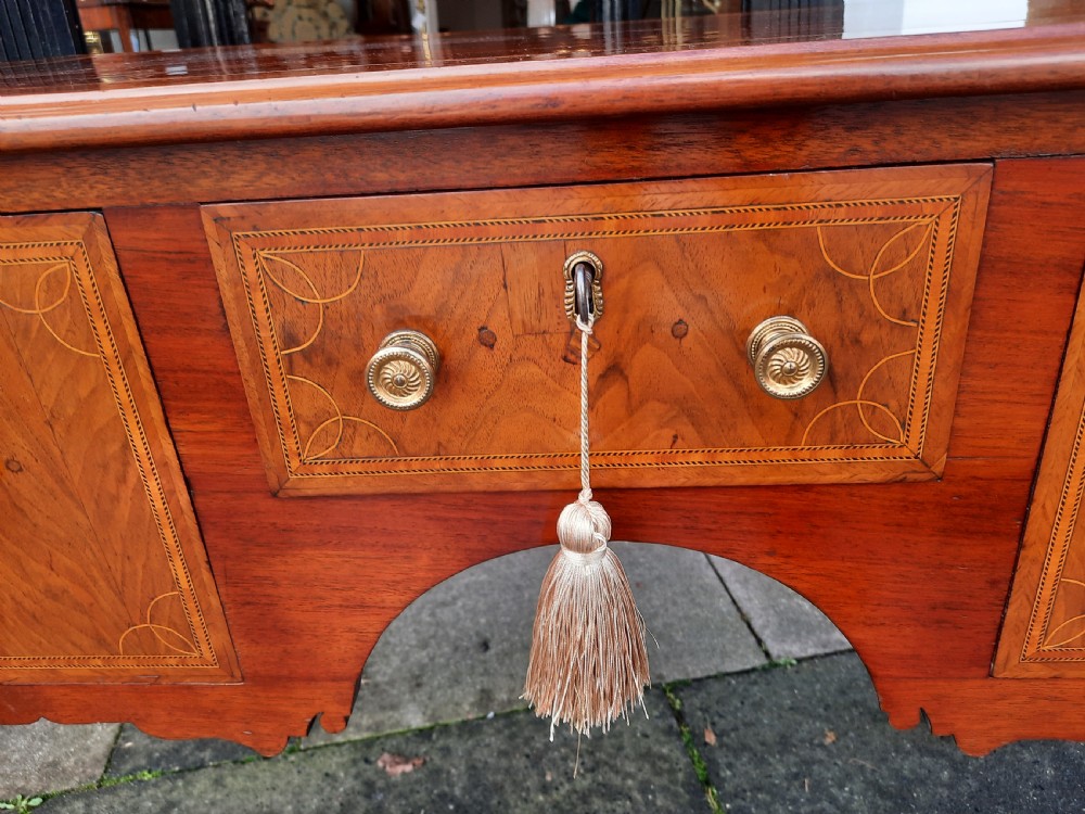 An Edwardian inlaid mahogany lowboy featuring three drawer fronts decorated with lighter wood inlay, an arched apron, and cabriole legs. View VI