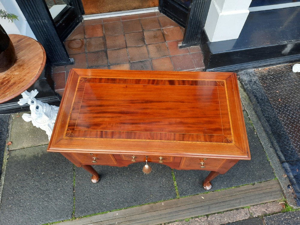 An Edwardian inlaid mahogany lowboy featuring three drawer fronts decorated with lighter wood inlay, an arched apron, and cabriole legs. View VII