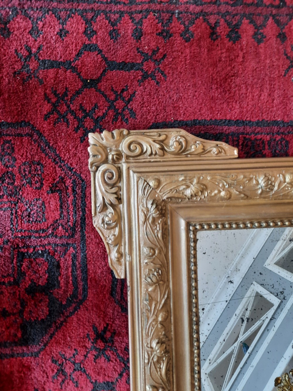 A rectangular 19th-century giltwood and gesso wall mirror featuring ornate foliate moulding and original foxed mirror glass. View II