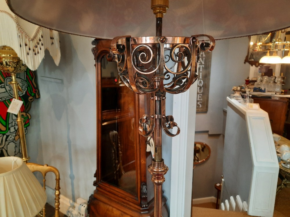 An Arts and Crafts copper floor lamp featuring an adjustable central stem, scrollwork base, and a patterned fabric shade. View IV