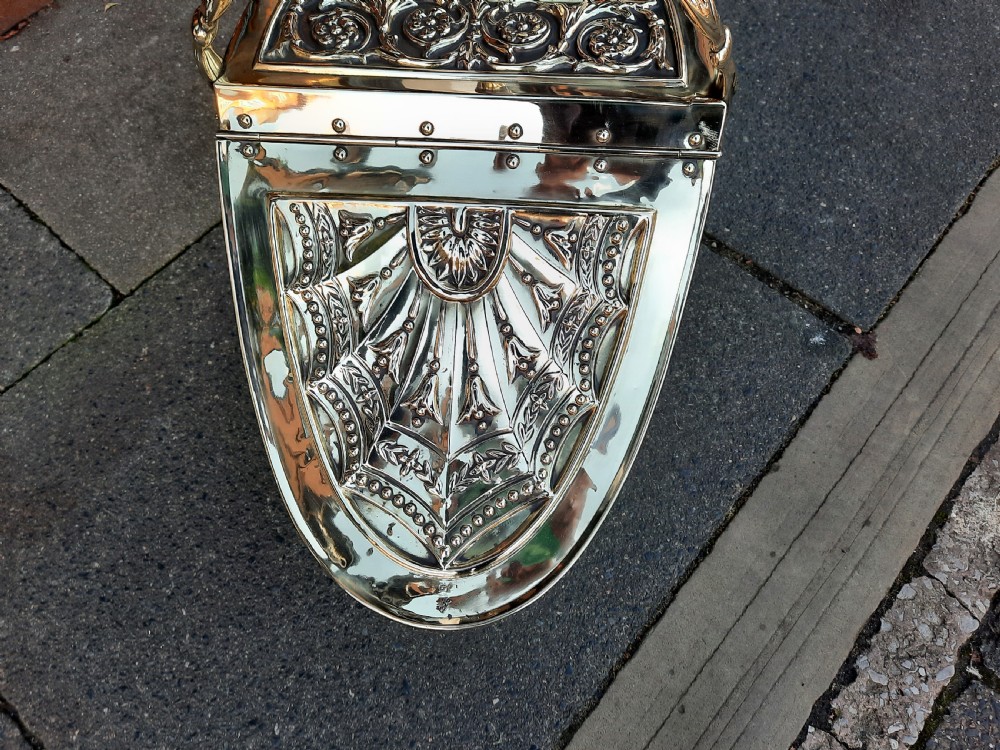 An antique brass coal purdonium in the Adam style, featuring intricate repousse classical motifs, a pedestal base, carrying handle, and attached shovel. View II