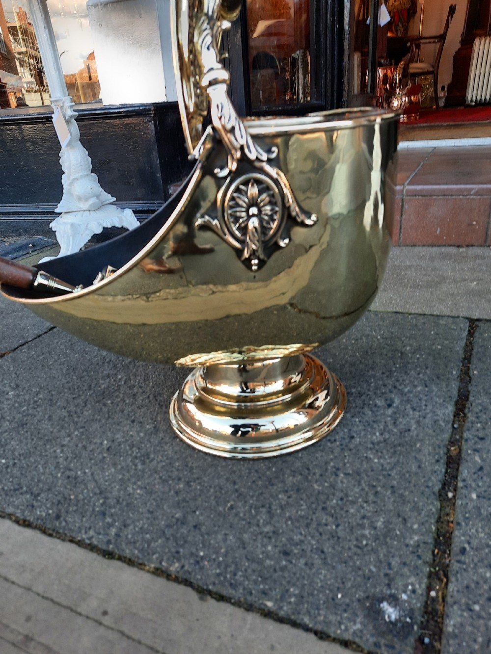 An antique brass coal purdonium in the Adam style, featuring intricate repousse classical motifs, a pedestal base, carrying handle, and attached shovel. View VI
