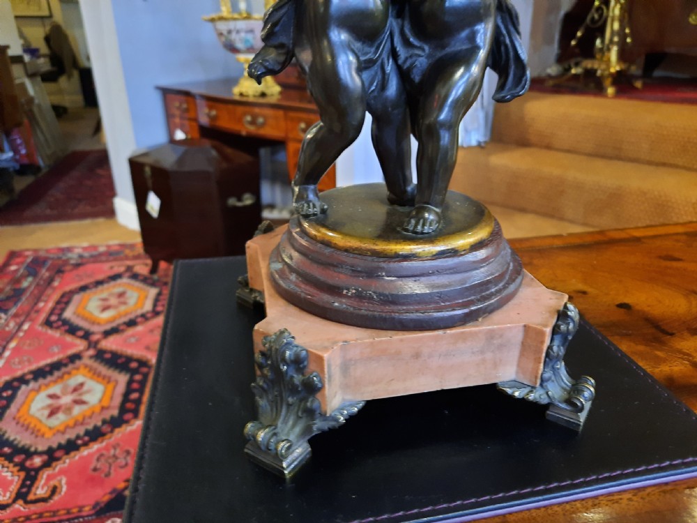 An antique French bronze table lamp with sculpted cherub figures resting on a marble base, topped with a cream and black scalloped fabric shade. View VII