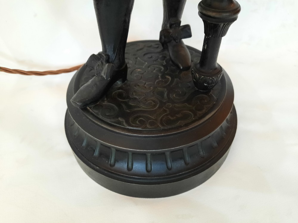 A pair of late nineteenth-century dark spelter table lamps featuring detailed cast musketeer figures supporting pike shafts fitted with cream shades. View III