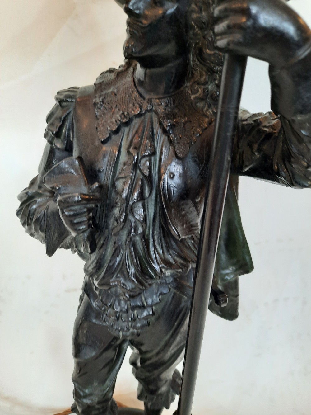 A pair of late nineteenth-century dark spelter table lamps featuring detailed cast musketeer figures supporting pike shafts fitted with cream shades. View IV