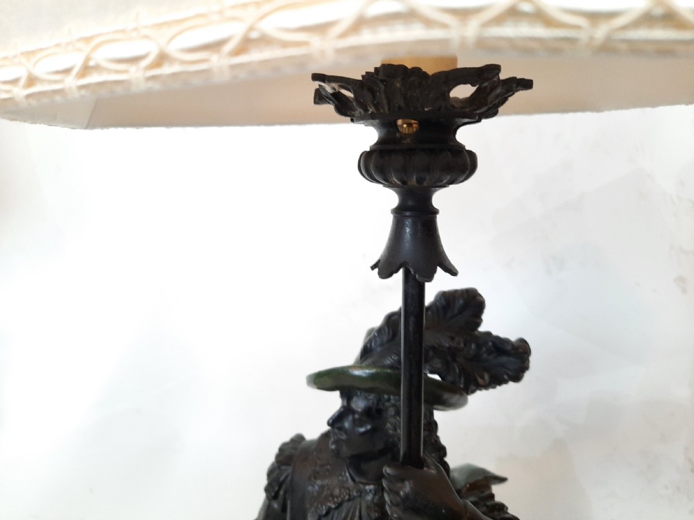 A pair of late nineteenth-century dark spelter table lamps featuring detailed cast musketeer figures supporting pike shafts fitted with cream shades. View VII