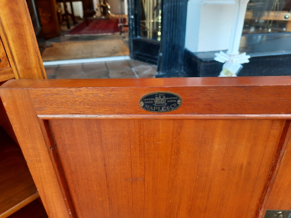 An Edwardian satinwood bedside cabinet featuring chevron pattern veneered door and drawer panels, metal drop handles, and tapered square legs. View VI