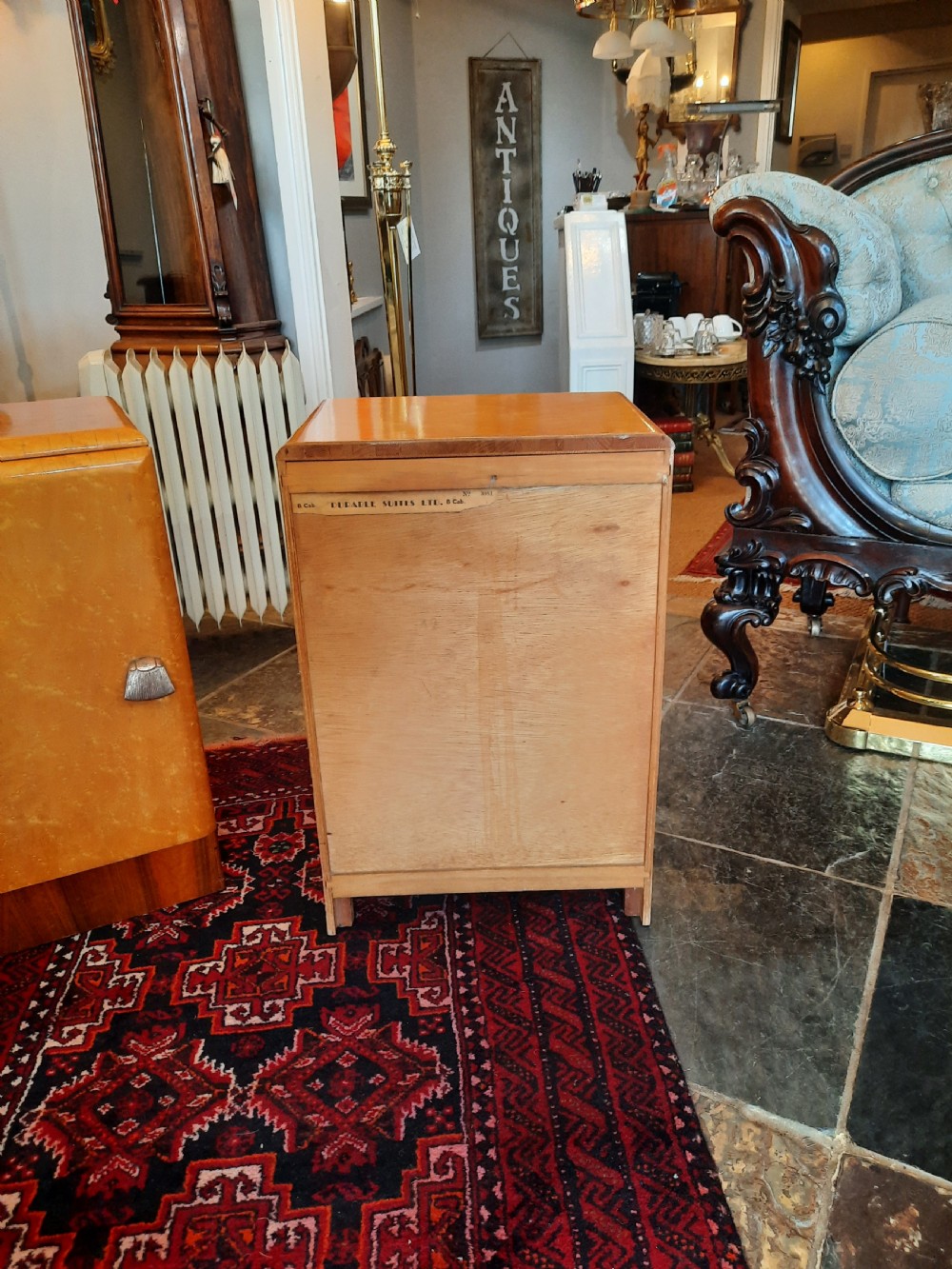 A pair of Art Deco bedside cabinets featuring golden parchment door fronts, contrast dark wood plinths, and small metal handles. View VI