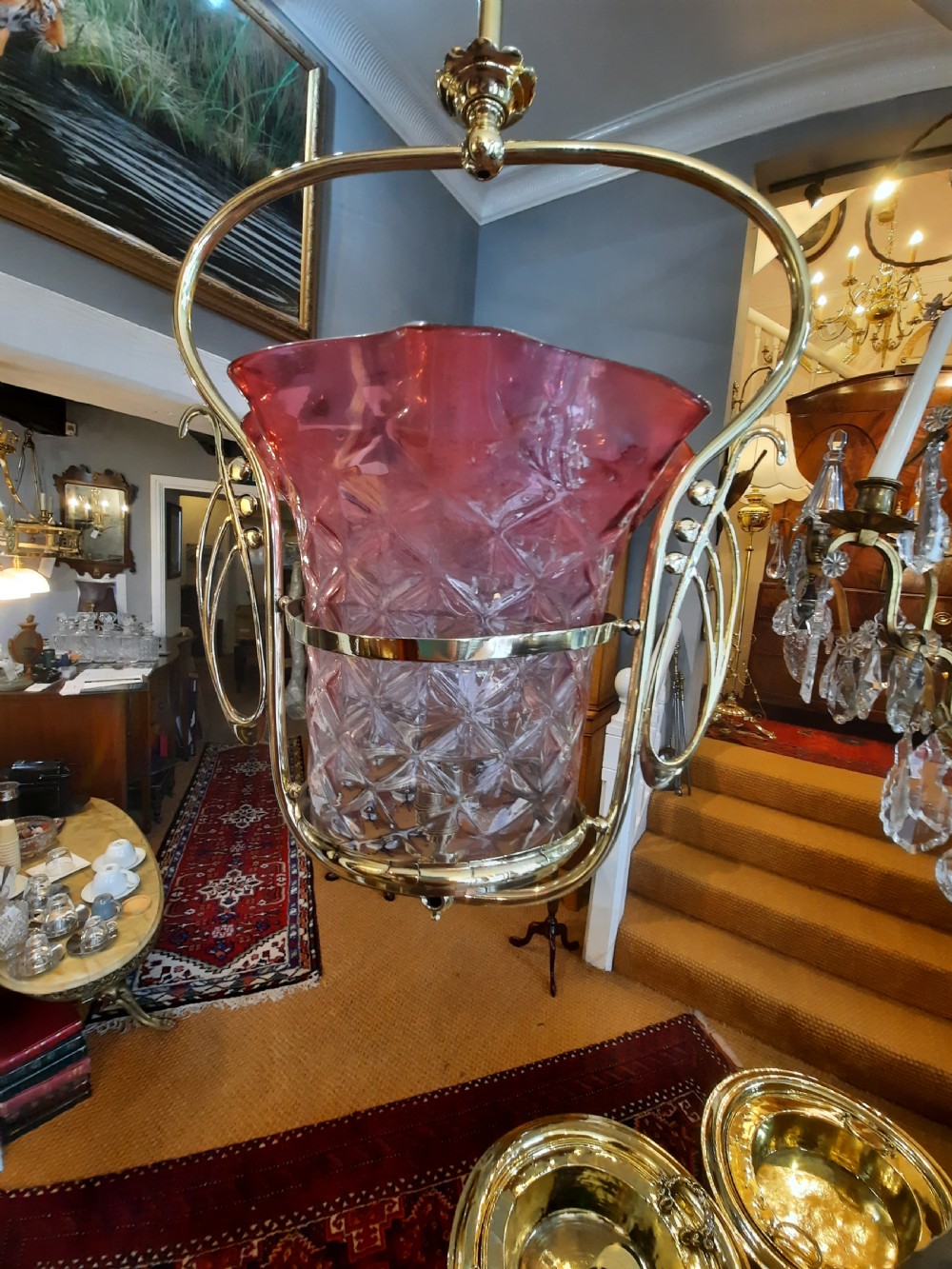 An Art Nouveau brass pendant light frame housing a ruffled cranberry glass shade with a moulded diamond pattern. View VI