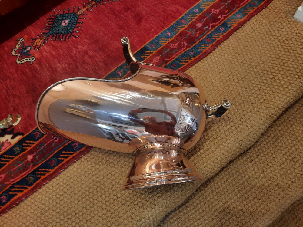 A polished copper Georgian coal helmet scuttle with turned wooden handles and a pedestal base. View VI