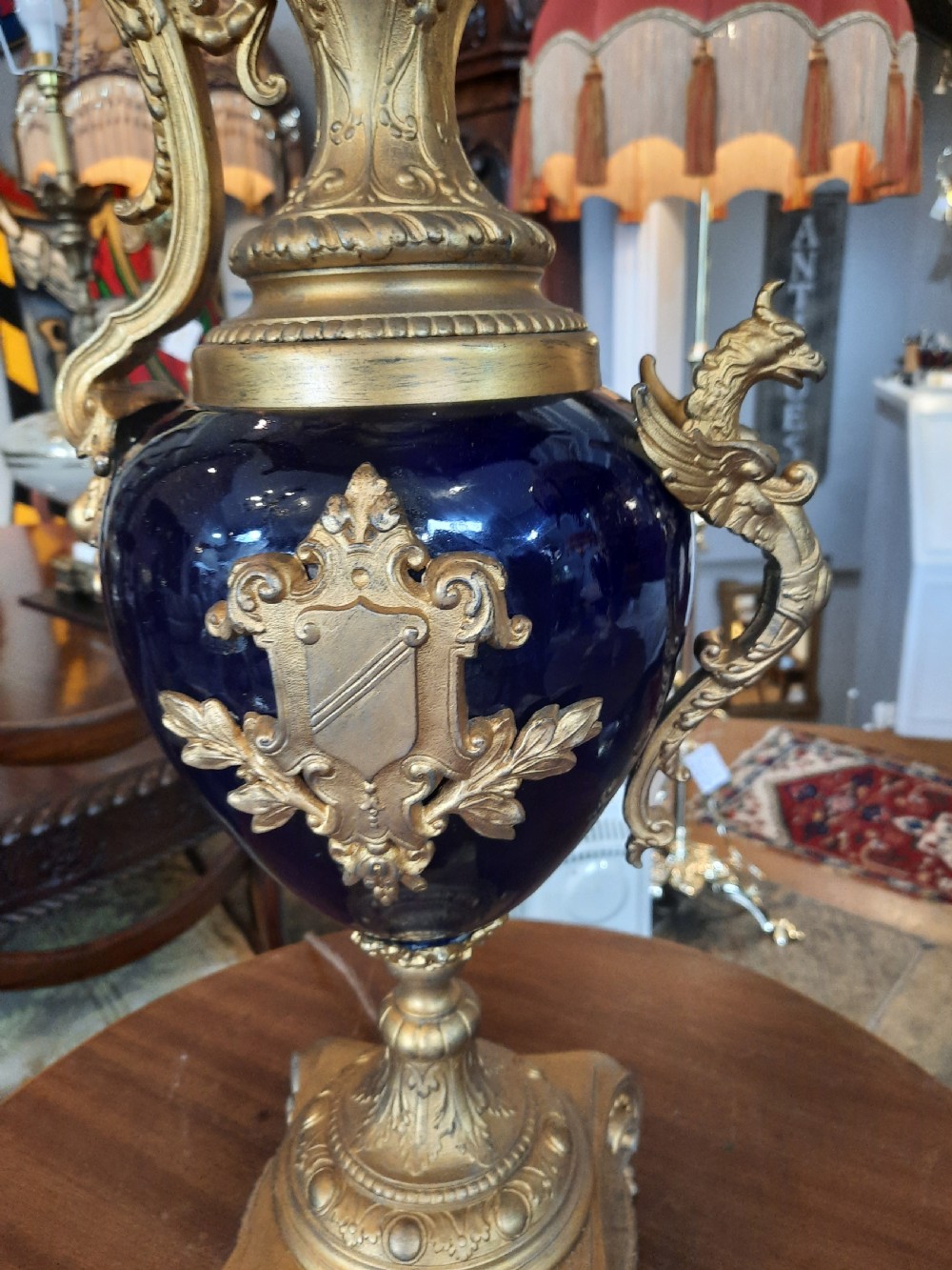 A pair of late nineteenth-century cobalt blue glass ewer lamps with ornate gilt bronze mounts and cream fabric shades featuring fringe and bead tassels. View IV