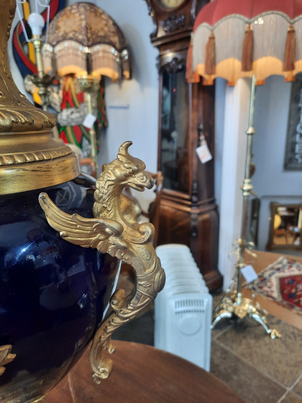 A pair of late nineteenth-century cobalt blue glass ewer lamps with ornate gilt bronze mounts and cream fabric shades featuring fringe and bead tassels. View V