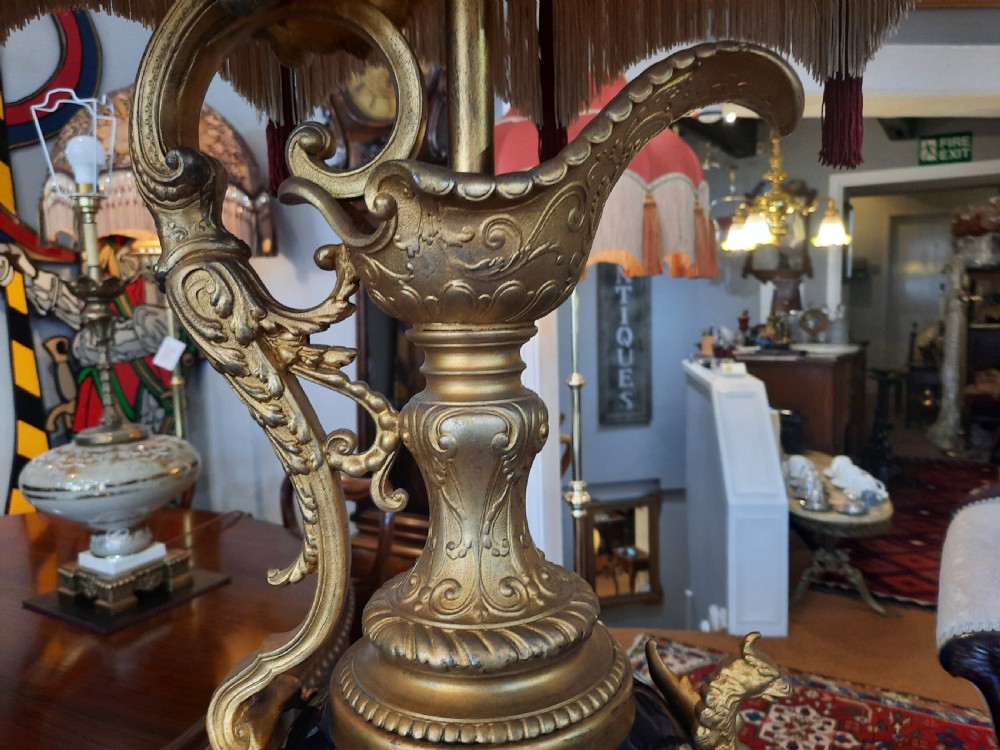 A pair of late nineteenth-century cobalt blue glass ewer lamps with ornate gilt bronze mounts and cream fabric shades featuring fringe and bead tassels. View VI