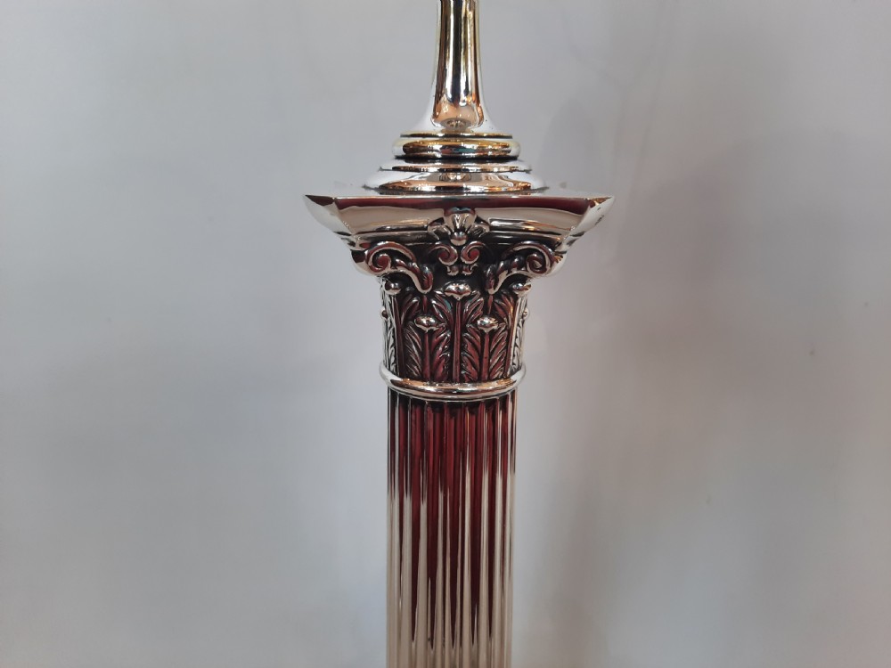 A silver-plated table lamp styled as a fluted Corinthian column with a stepped square base, topped with a scalloped pink fabric shade adorned with long beaded fringe. View V