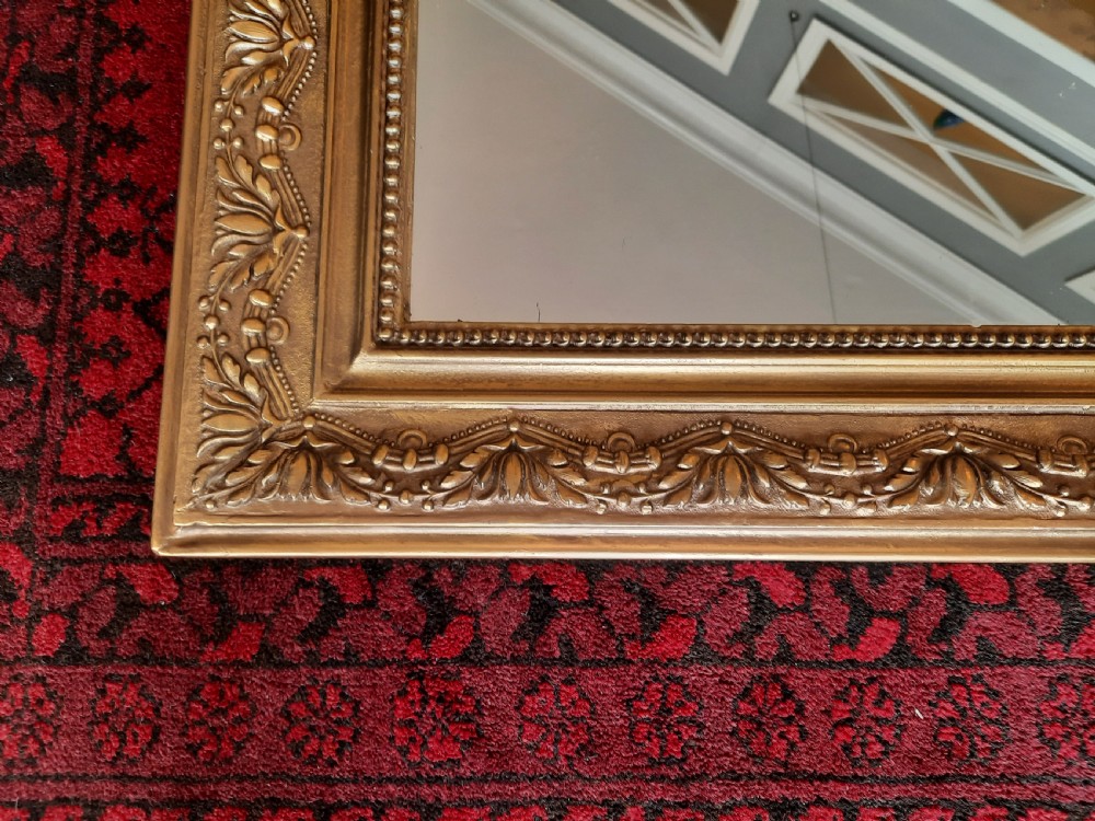 A 19th-century French gilded wall mirror featuring an arched frame topped with a carved crest of winged dragons and a central shield. View IV