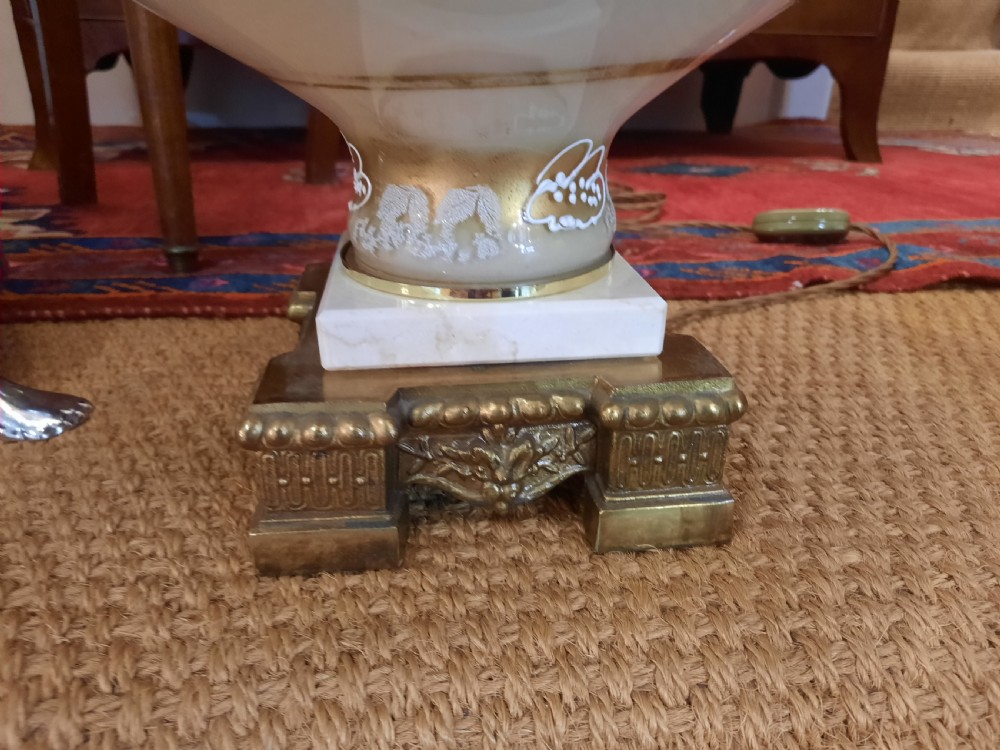 A pair of late Victorian table lamps featuring ornate gilt brass stems, painted glass baluster bases, and cream silk shades with fringe tassels. View II