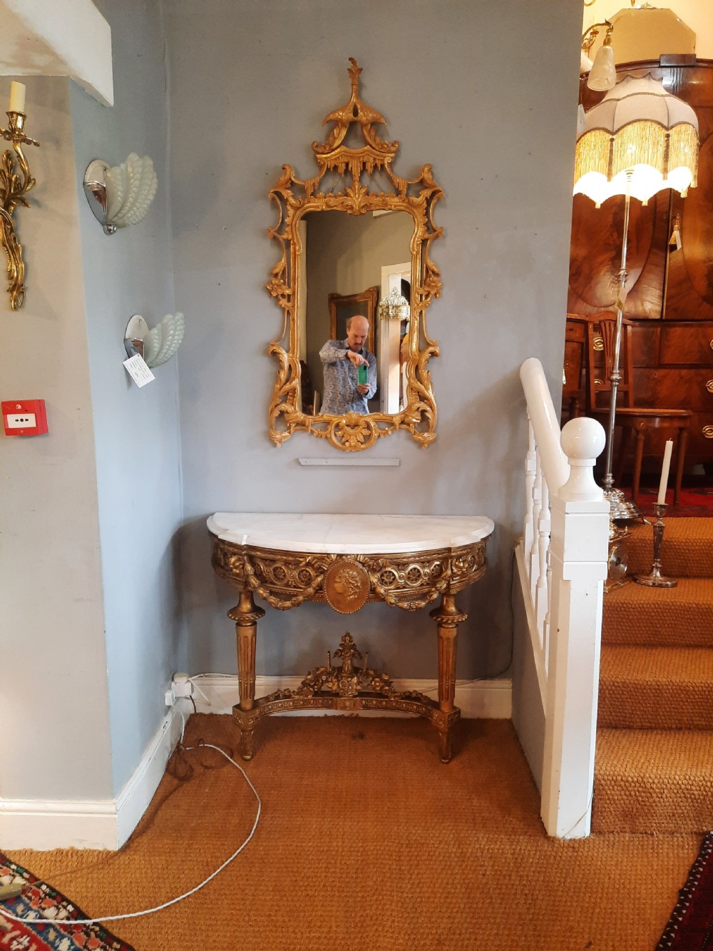 An early 19th-century semicircular giltwood console table featuring a white marble top, carved classical medallion, decorative swags, and fluted legs. View II