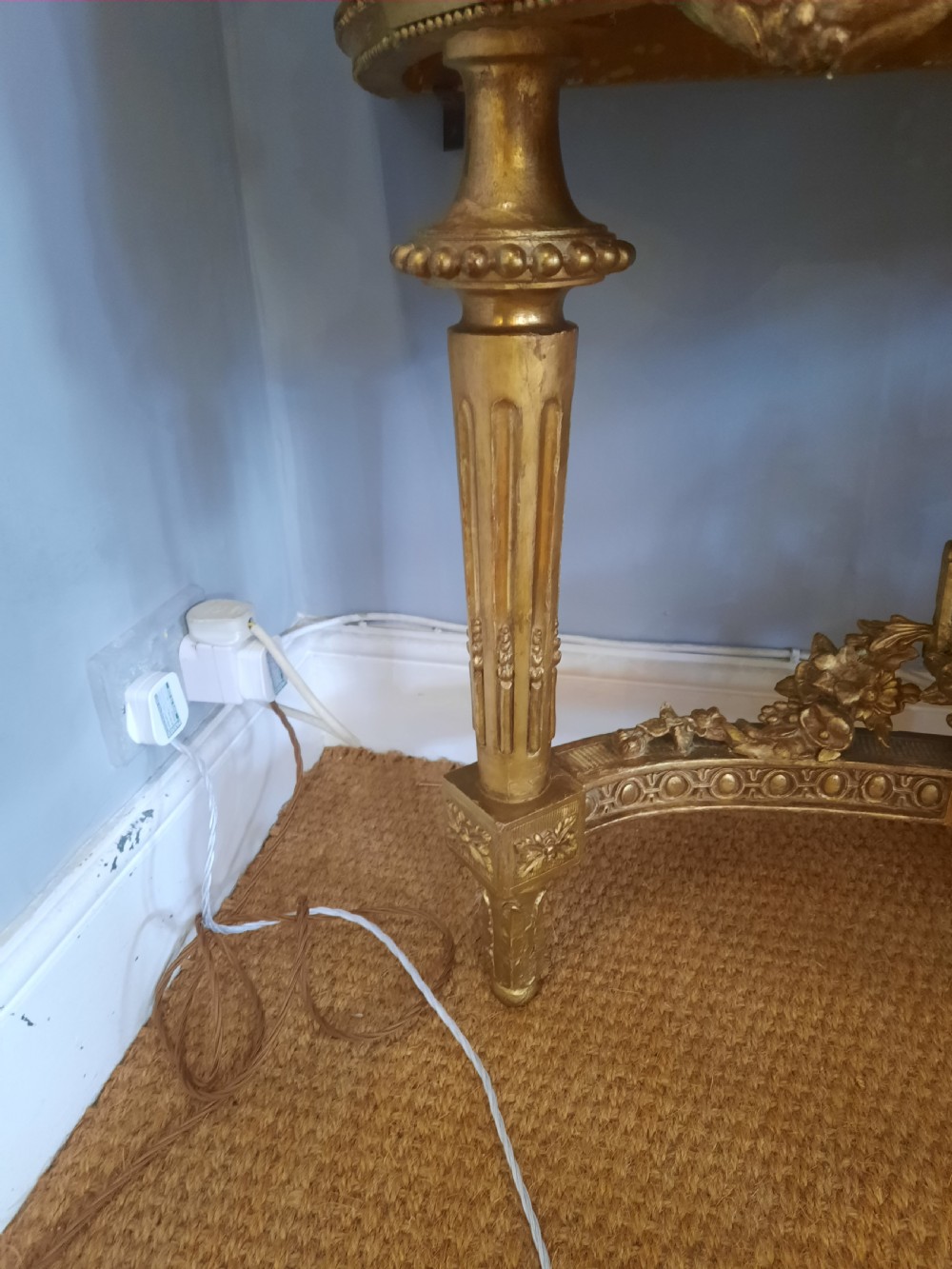 An early 19th-century semicircular giltwood console table featuring a white marble top, carved classical medallion, decorative swags, and fluted legs. View V