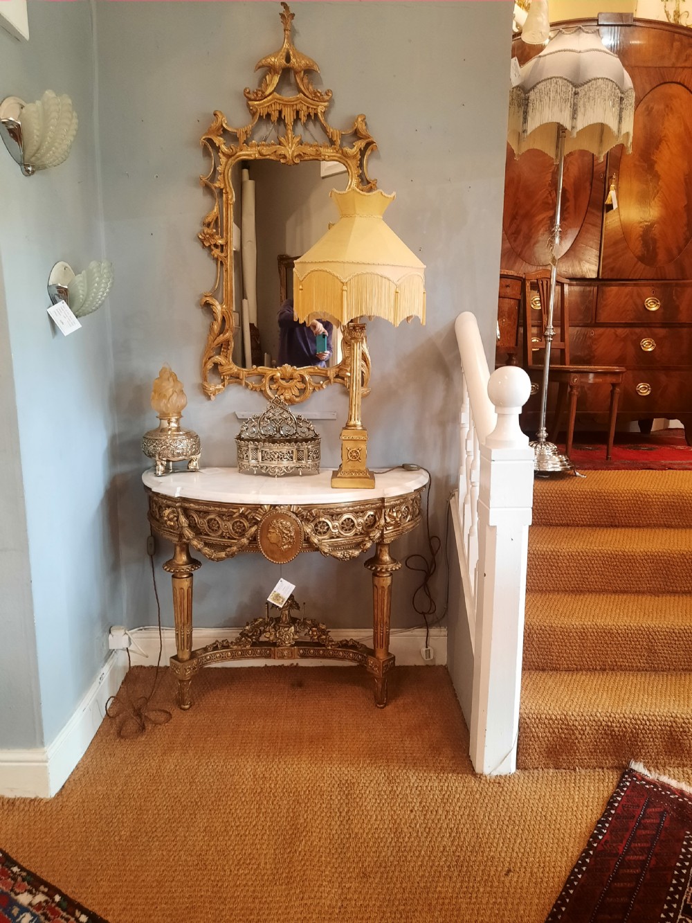 An early 19th-century semicircular giltwood console table featuring a white marble top, carved classical medallion, decorative swags, and fluted legs. View VIII