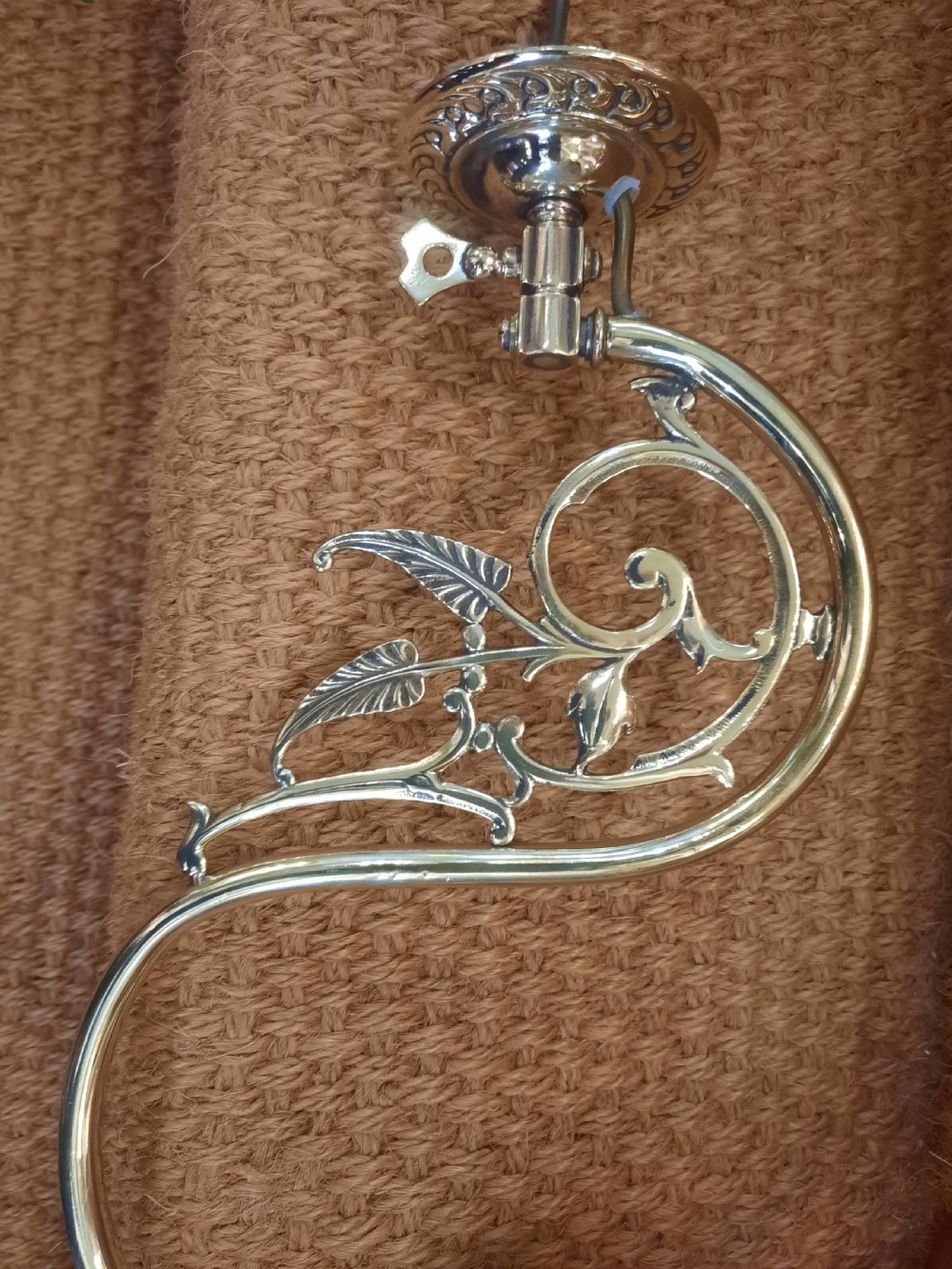 A pair of Art Nouveau brass wall lights featuring foliate scrolled arms and fluted cranberry glass shades. View II