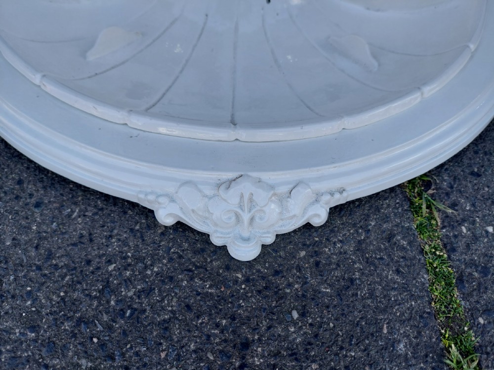A white painted cast iron Victorian stick stand featuring detailed scrollwork, an arched backplate frame with a top ring, a central pedestal, and a curved drip tray base. View VI