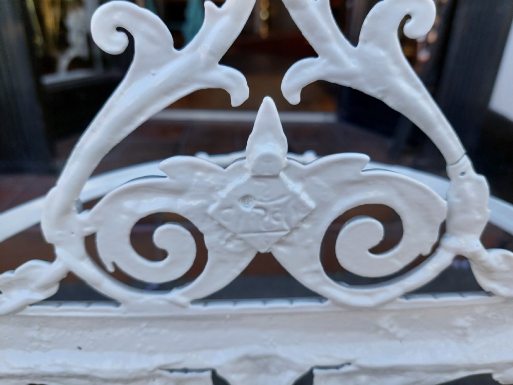 A white painted cast iron Victorian stick stand featuring detailed scrollwork, an arched backplate frame with a top ring, a central pedestal, and a curved drip tray base. View VIII