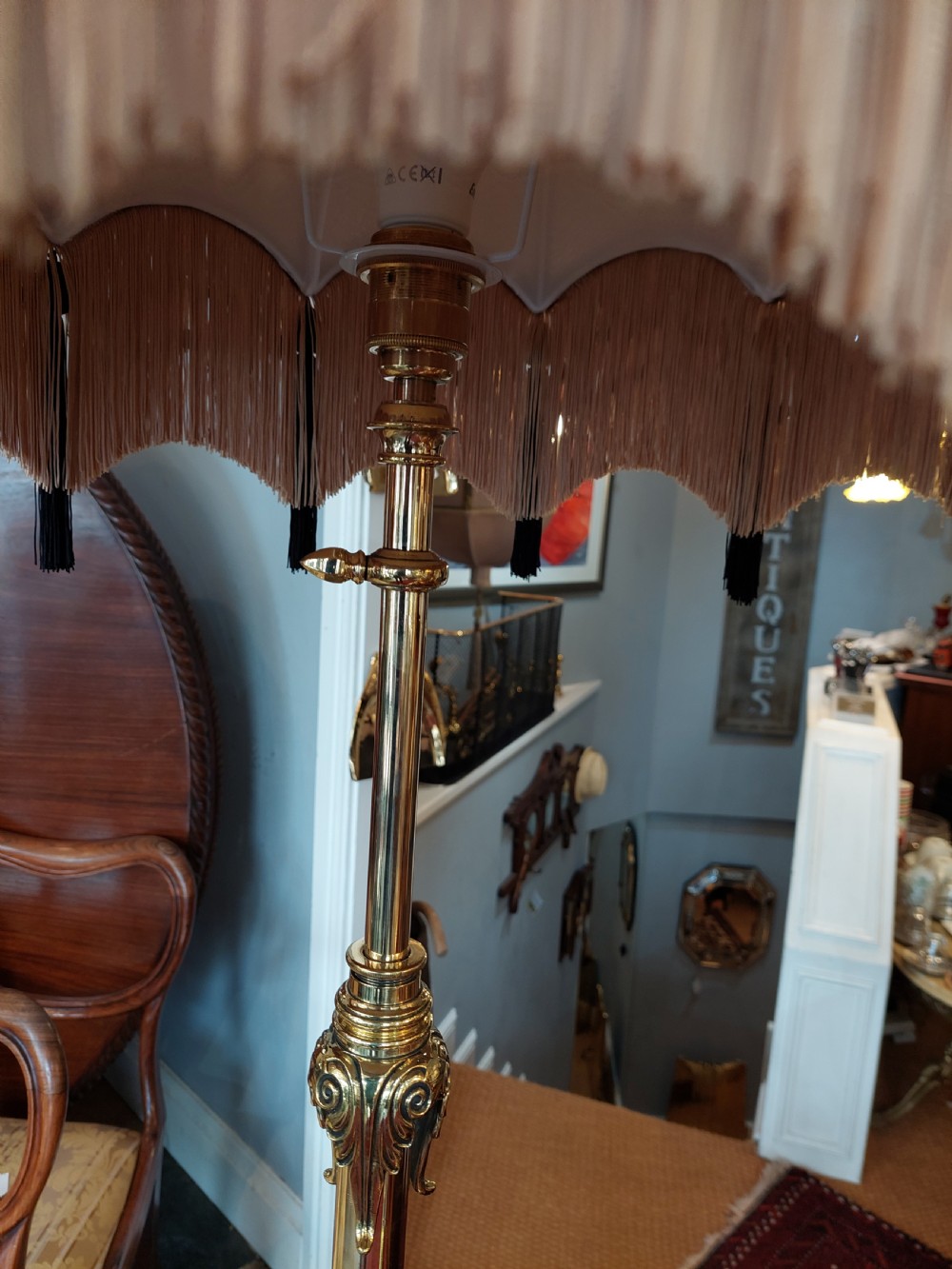 A late Victorian brass and copper extending standard floor lamp featuring a scrolled tripod base and a cream fringed shade. View V