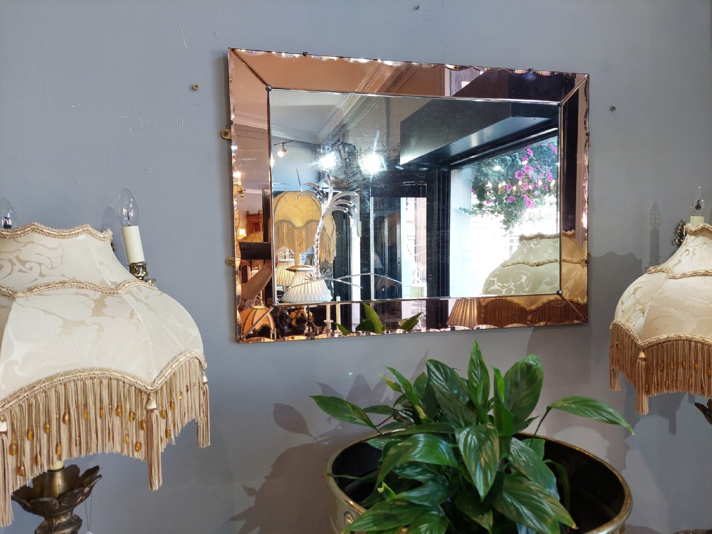 A rectangular Art Deco wall mirror featuring a peach-tinted glass border with scalloped outer edges and an etched palm tree design in the bottom corner. View V