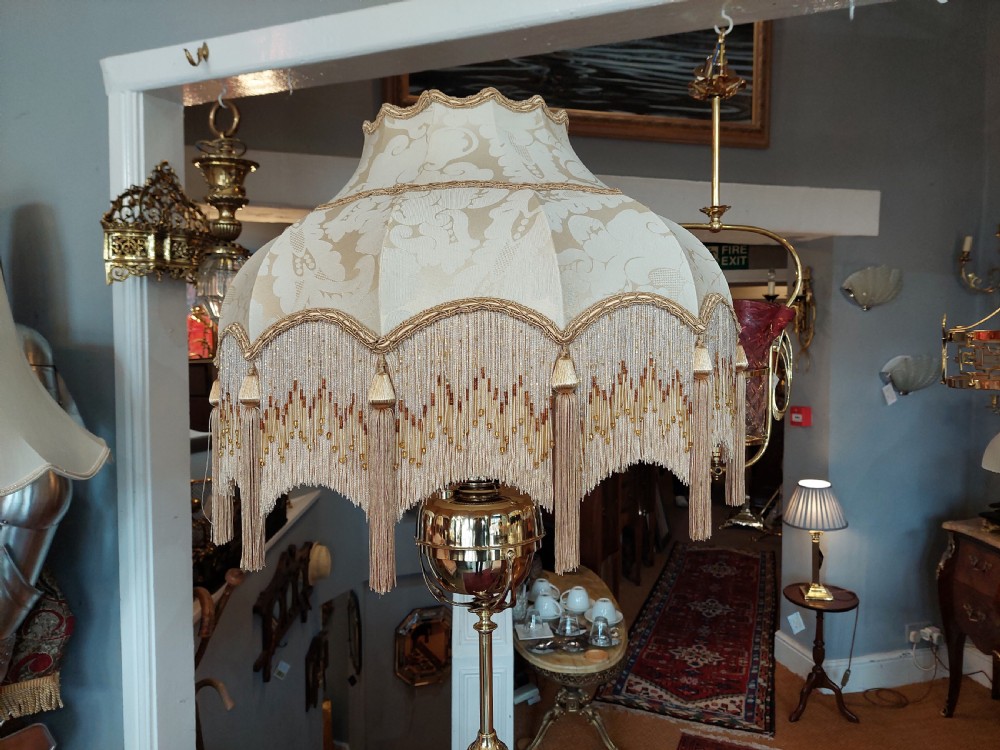 An Art Nouveau brass adjustable standard lamp with a tripod base, telescopic central stem, and a cream fringed fabric shade. View II