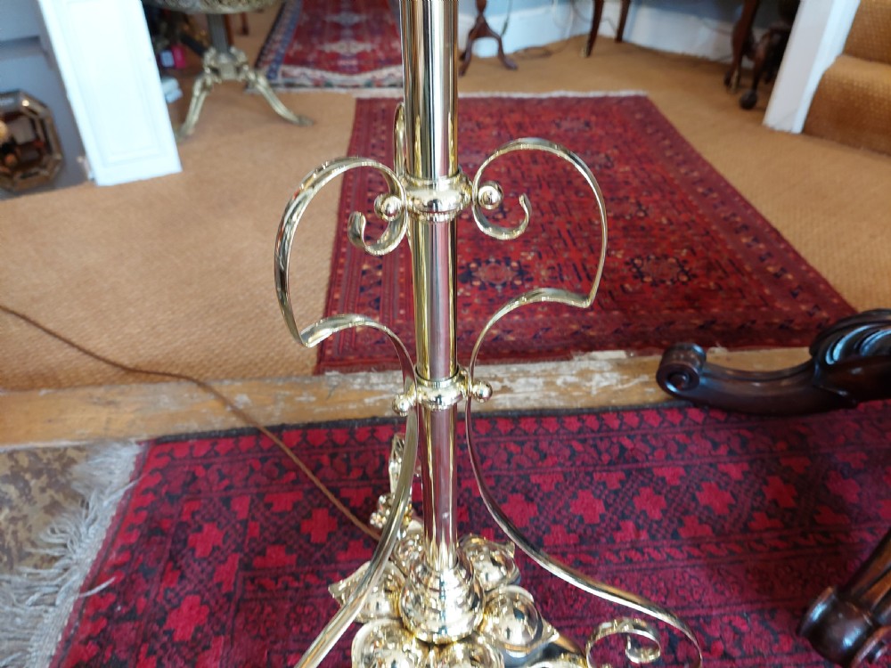 An Art Nouveau brass adjustable standard lamp with a tripod base, telescopic central stem, and a cream fringed fabric shade. View VI